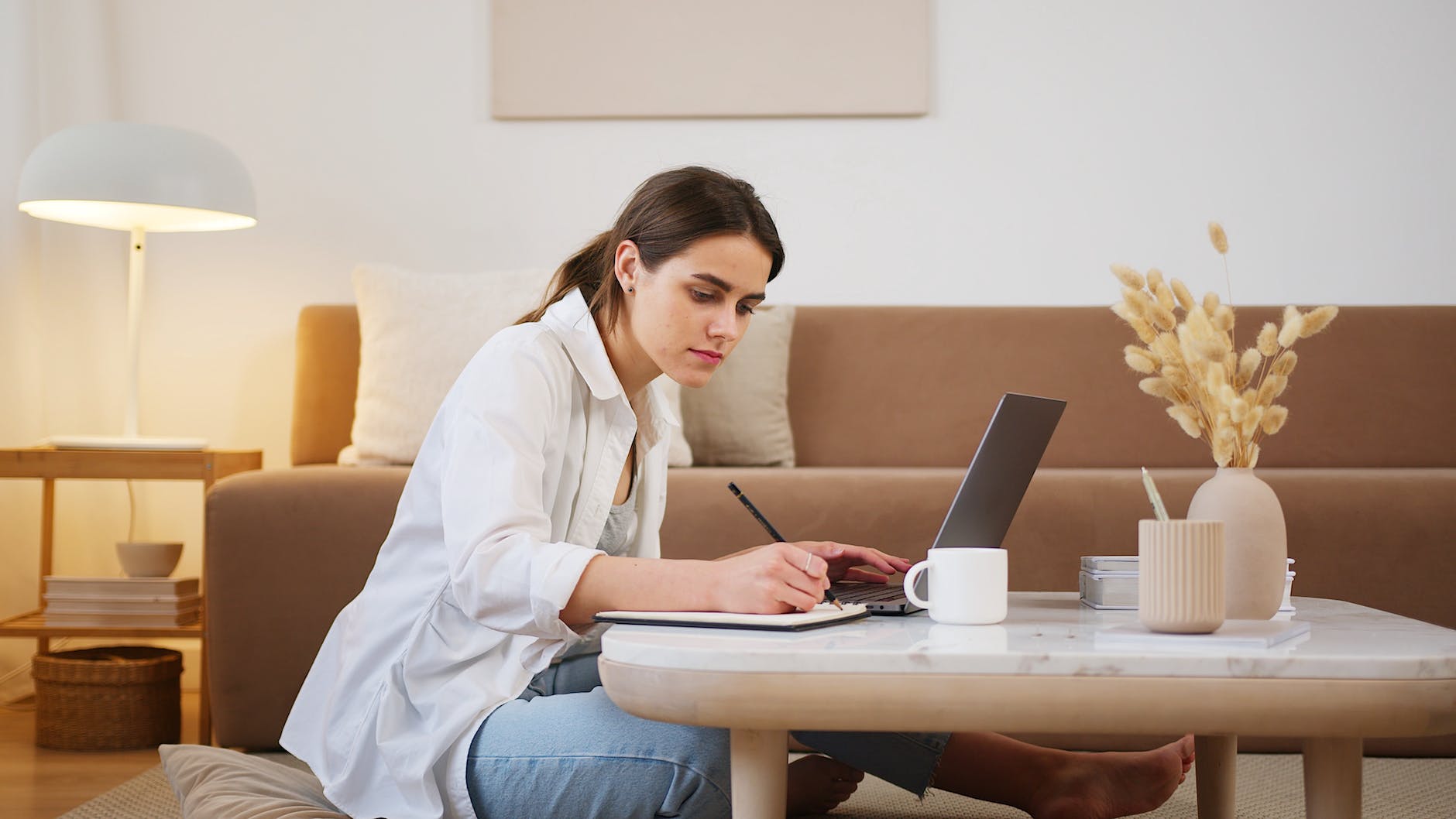 young woman using laptop and taking notes