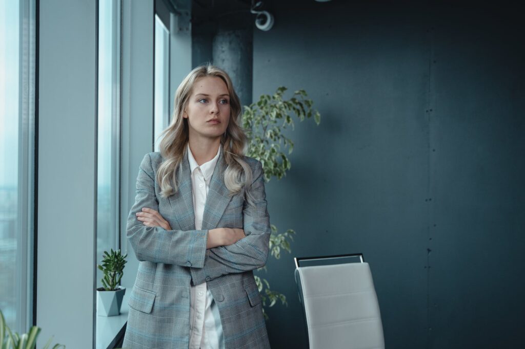 woman in gray blazer standing by the window