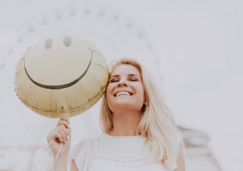 woman holding a smiley balloon