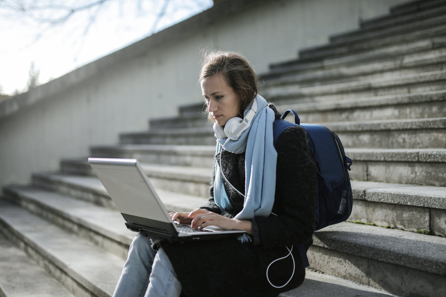 woman sitting on concrete stairs using laptop