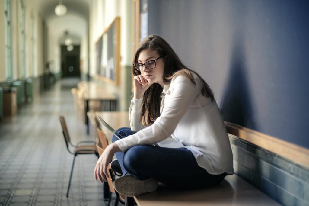 woman in white long sleeve shirt and blue denim jeans sitting on table