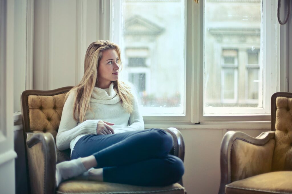 photography of woman sitting on chair near window