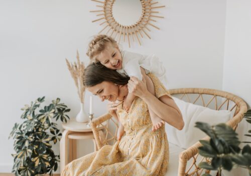 woman in yellow floral dress with baby girl hugging her