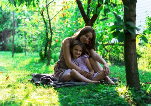 mother and daughter sitting on a blanket outside