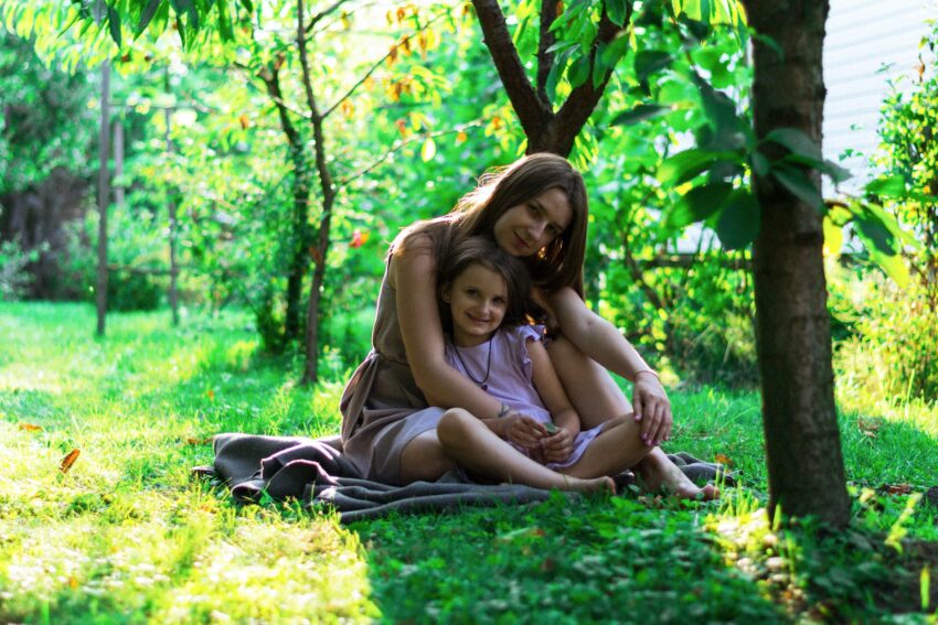 mother and daughter sitting on a blanket outside