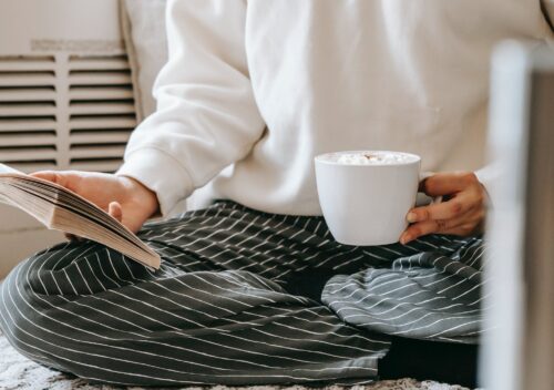 crop woman with book drinking coffee