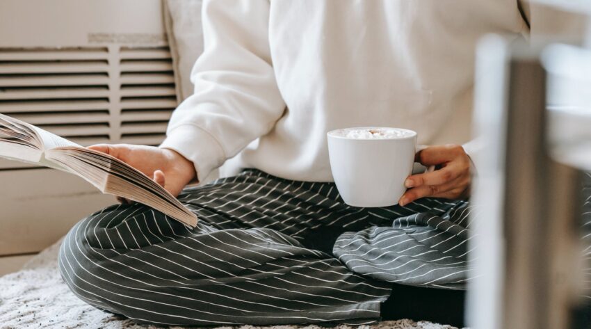 crop woman with book drinking coffee